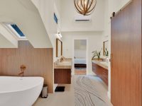 Modern luxury bathroom with freestanding white bathtub, double vanity, wooden accents, skylight, and marble flooring