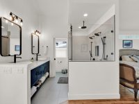 Modern master bathroom with double vanity, walk-in shower, navy blue cabinetry, and wood flooring
