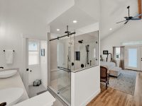 Modern primary bathroom with walk-in shower, double vanity, freestanding tub, and wood-look flooring throughout the space