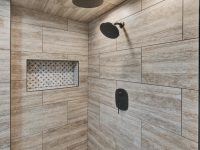 Modern bathroom shower with wood-grain tile walls, rainfall showerhead, body jets, niche storage, and recessed ceiling lights