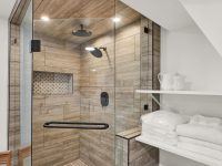 Modern walk-in shower with glass enclosure, marble tile, and chrome fixtures in a contemporary attic bathroom