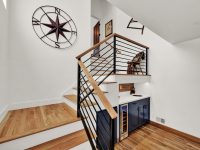 Modern loft bedroom with wooden stairs, metal railings, floating shelves, compass wall decal, and hardwood flooring