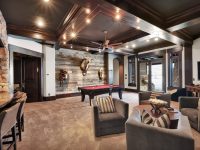 Luxurious basement game room with pool table, bar seating, comfortable lounge furniture, stone accents, and ambient lighting