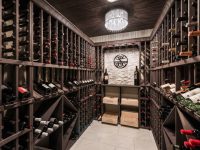 Custom wine cellar with wooden racks filled with wine bottles and wooden crates along both sides under warm lighting