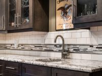 Modern kitchen countertop with white subway tile backsplash, granite counters, and dark cabinetry with glass doors