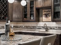Modern kitchen with dark wood cabinetry, granite countertop island, pendant lights, and marble backsplash with bar seating