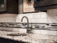 Modern kitchen with white subway tile backsplash, granite countertop, and chrome faucet above stainless steel sink