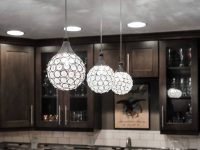 Modern kitchen with dark cabinetry, white marble countertop, and three crystal sphere pendant lights hanging above the island