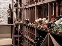 Wine bottles and glasses stored on wooden shelves in a dark cellar or wine storage room